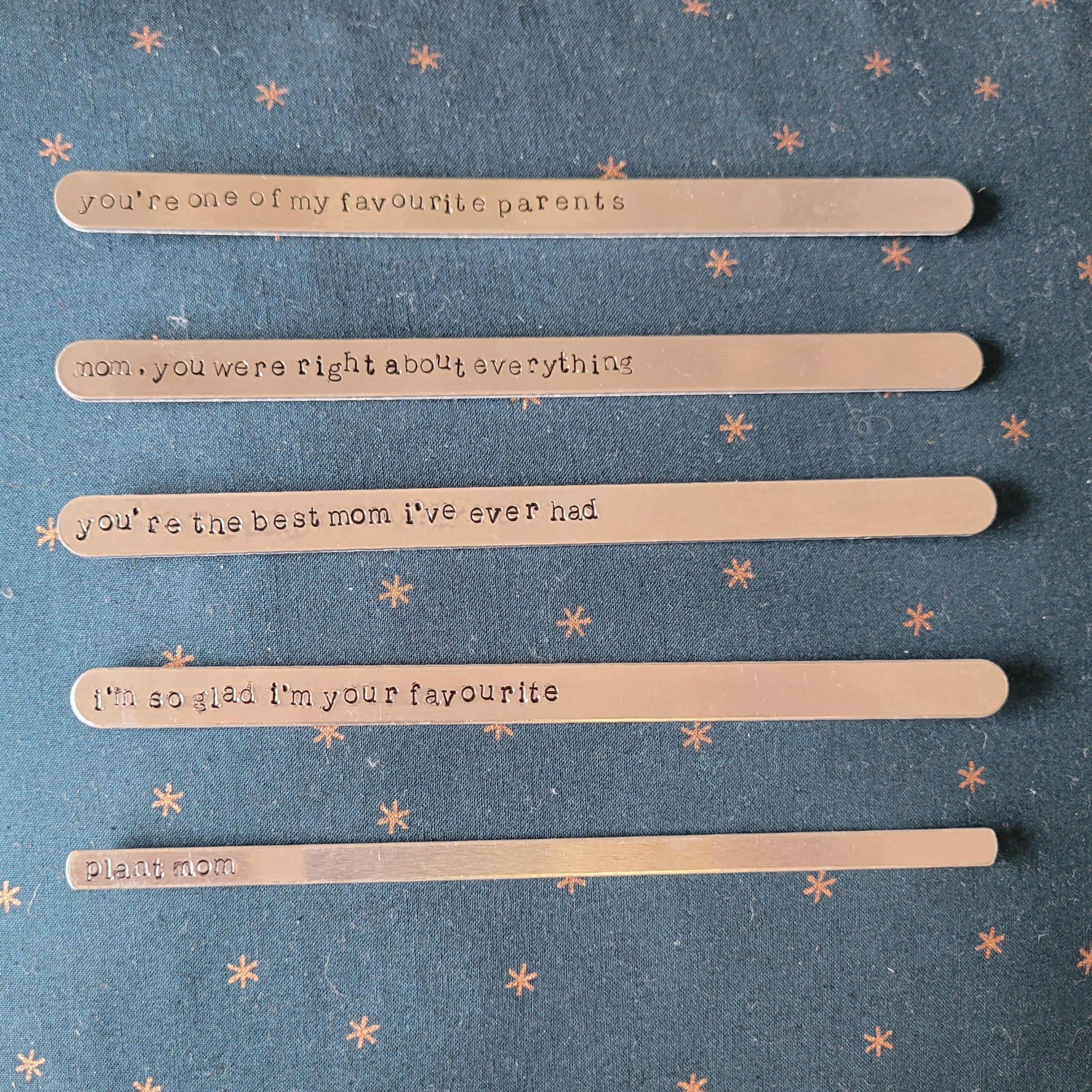 20210429_161212_2 Five aluminum sticks with different stamped slogans readings: 1. You're one of my favourite parents, 2. Mom, you were right about everything, 3. You're the best mom I've ever had, 4. I'm so glad I'm your favourite, and 5. Plant mom.